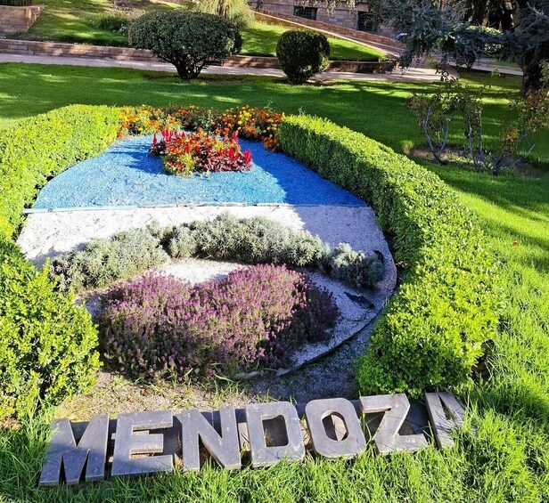 A landscaped garden with a colorful flower bed and the word 'MENDOZA' in stone letters. 4