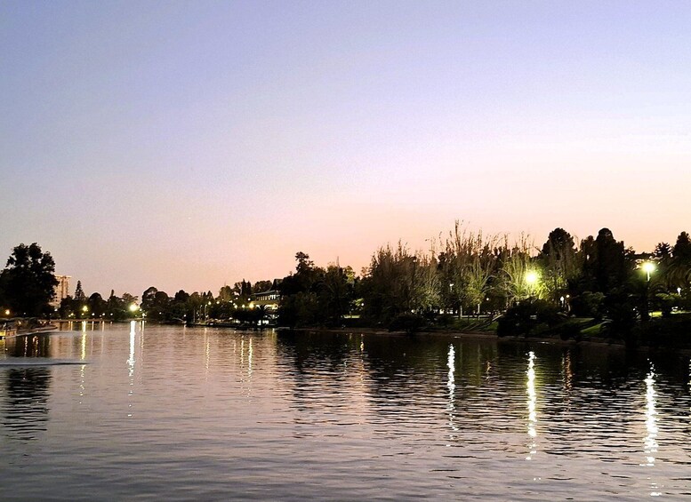 A calm lake at dusk with reflections of street lights and trees. 5