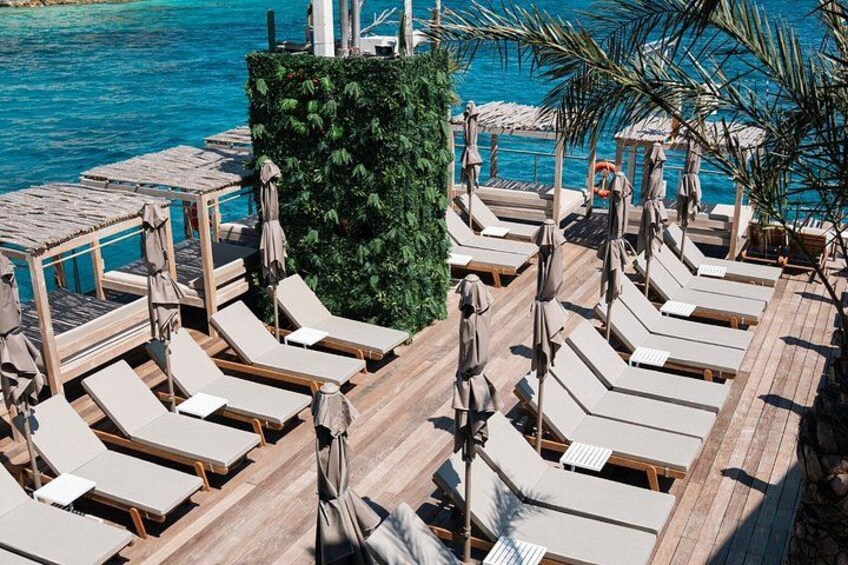 A wooden deck with lounge chairs and umbrellas by a pool. 2