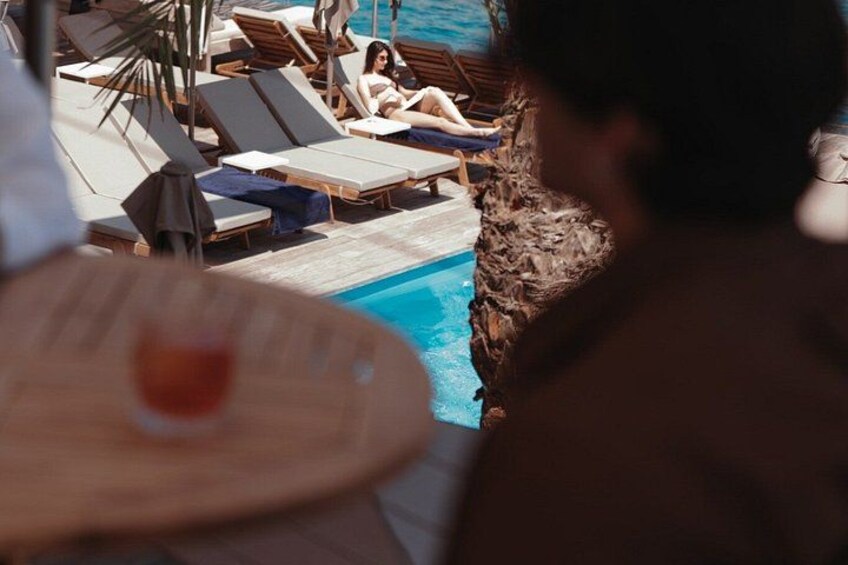 A poolside area with lounge chairs and a drink on a table. 5