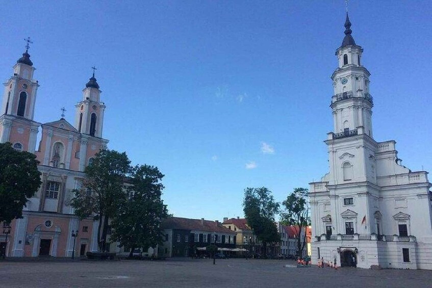 A historic square with two prominent churches, one with pink and white architecture and the other white with a tall bell tower. 3