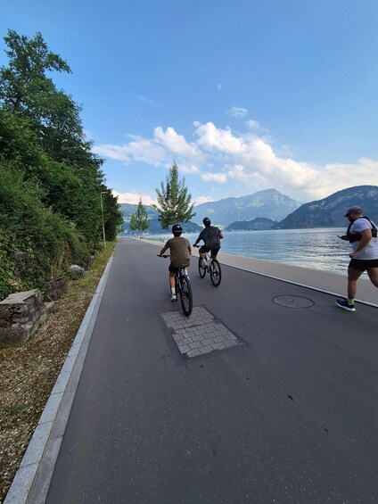 A paved bike path alongside a lake with mountains in the background. 4
