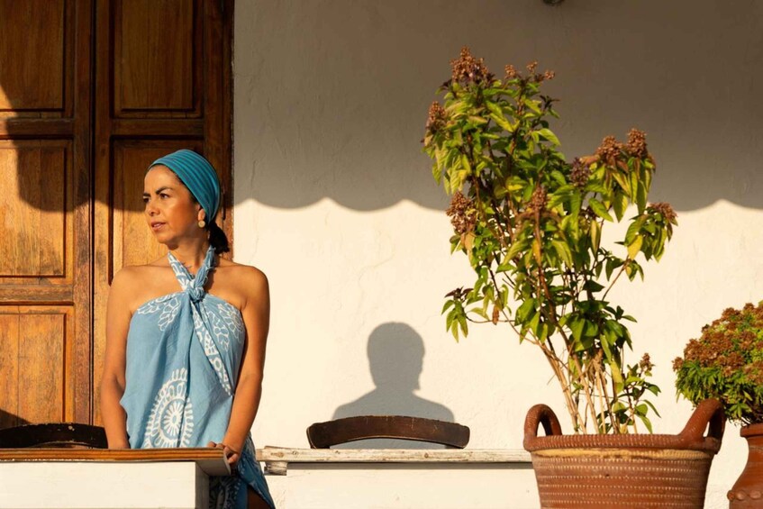 A person standing in front of a wooden door, with a potted plant to the right. 2