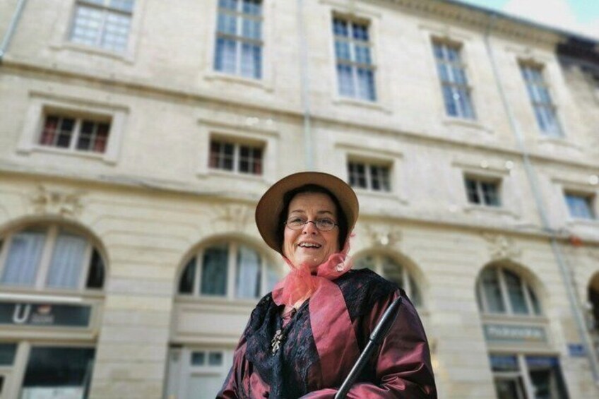 A person standing in front of a historic building with arched windows and a stone facade. 5