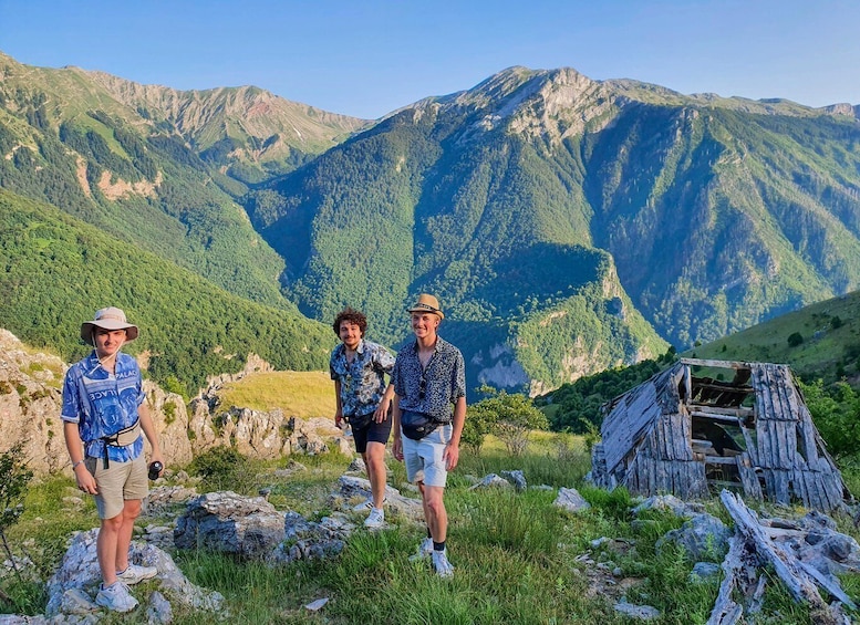 Three people standing on a rocky outcrop with a mountainous landscape in the background. 4