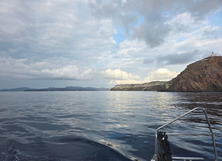 Calm sea waters, a rocky coastline, and a distant mountain range under a cloudy sky. 4