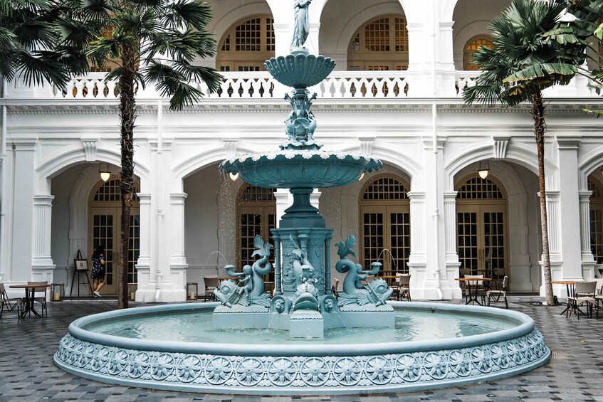 A fountain with ornate sculptures in a courtyard with white buildings and palm trees. 3