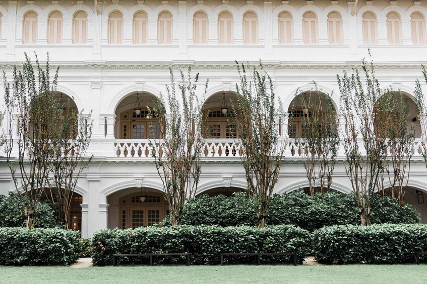 A white building with arched windows and a central courtyard with trees and a bench. 4