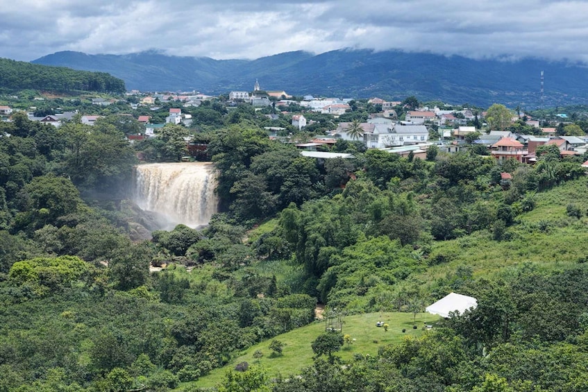A waterfall cascading down a lush hillside, surrounded by a village with houses and a church. 3