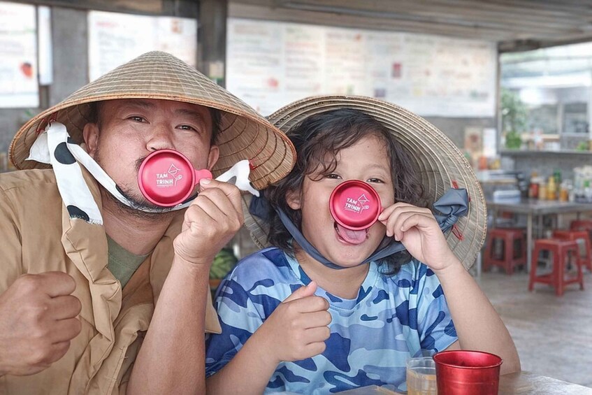 Two people wearing conical hats, sitting at a table with a menu in the background. 1