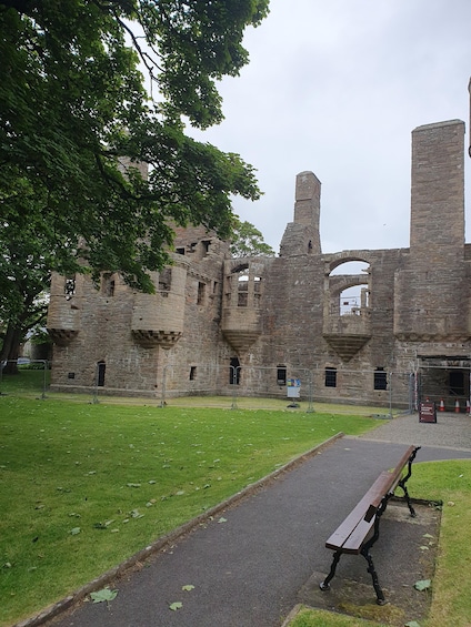 An ancient stone castle with a grassy courtyard and a bench. 2