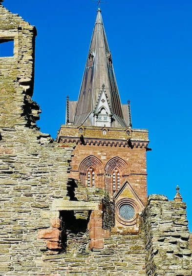 A historic stone building with a pointed spire and arched windows. 1