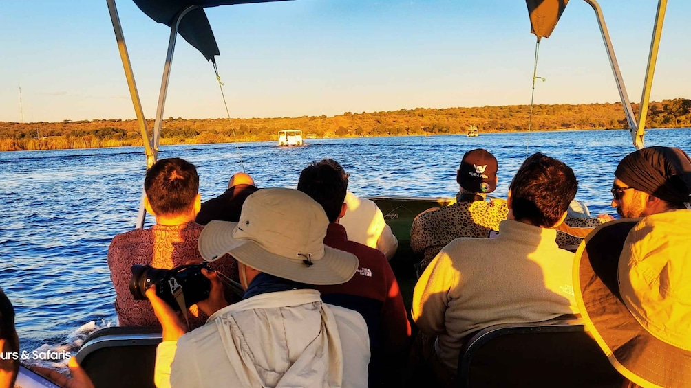 A group of people on a boat, with a river and trees in the background. 2