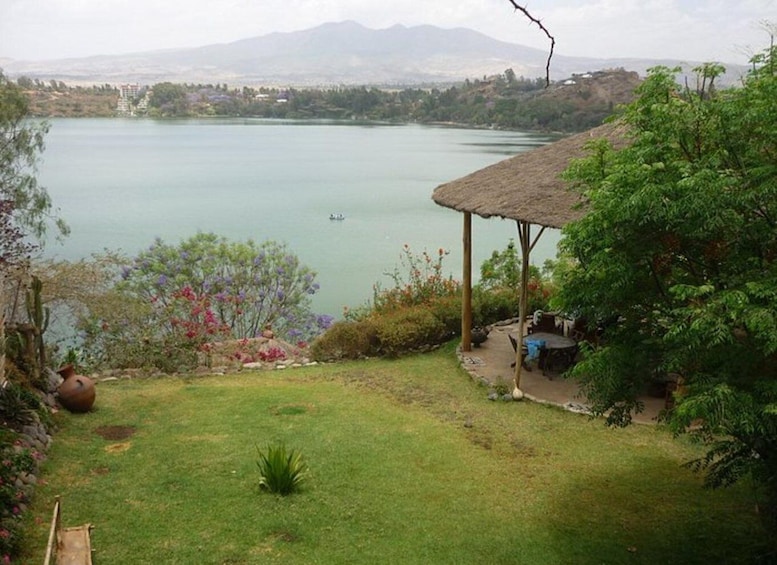 A lake with a gazebo, a boat, and mountains in the background. 3