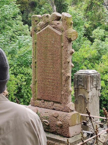 A weathered stone monument with intricate carvings, surrounded by lush greenery. 5