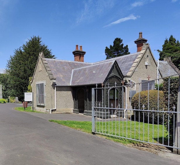 A small church with a stone facade, a metal fence, and a clear blue sky. 1