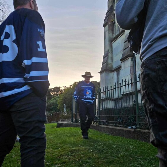 A person walking on a grassy path in a park with a statue in the background. 2