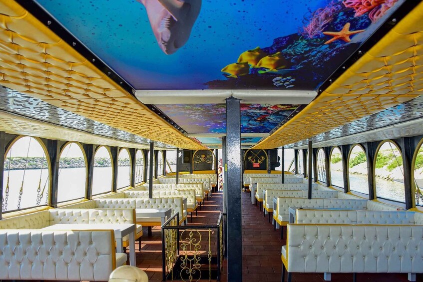 An interior with white cushioned seating, a central pillar, and a ceiling mural of underwater scenes. 5