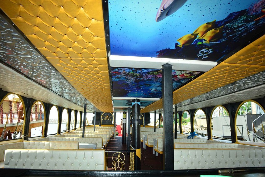 A boat interior with yellow and white seating, a large screen displaying an underwater scene, and a ship's wheel. 2