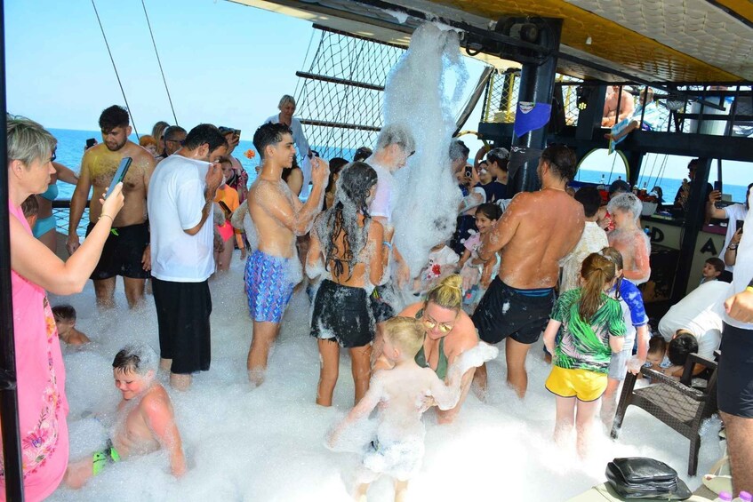 A group of people on a boat with foam being sprayed, likely for entertainment. 1