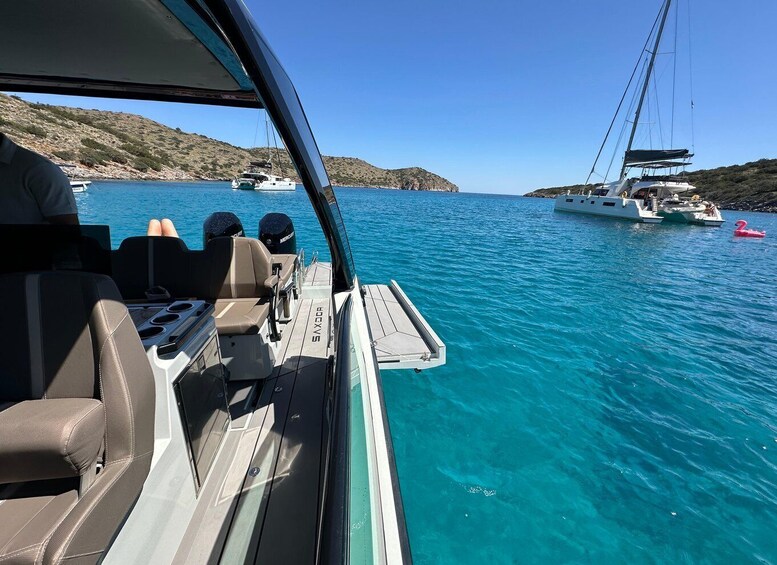 A boat with a clear view of the sea, other boats, and a rocky coastline. 5