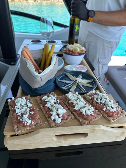 A tray with bruschetta, a bottle of olive oil, and a bowl of fruit on a boat. 2