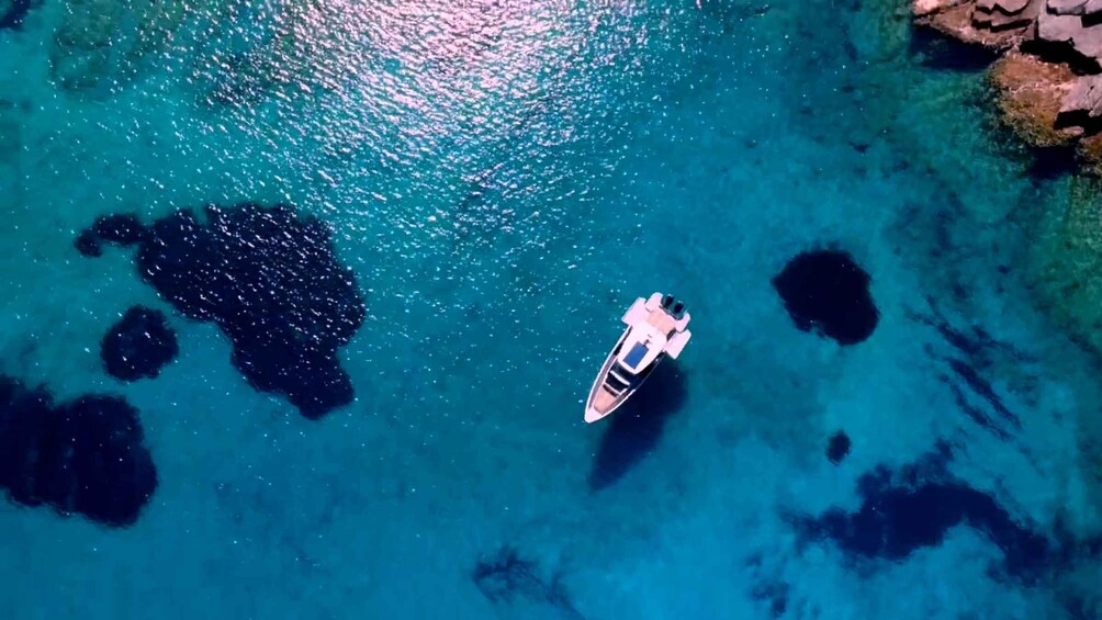 A boat on clear turquoise water with rocky formations. 1