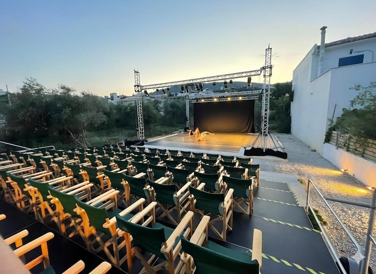 An outdoor amphitheater with a stage, seating, and a backdrop. 5