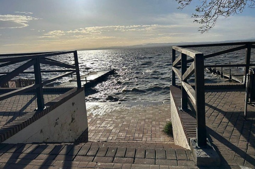 A seaside promenade with a wooden walkway, a stone-paved area, and a view of the ocean. 5