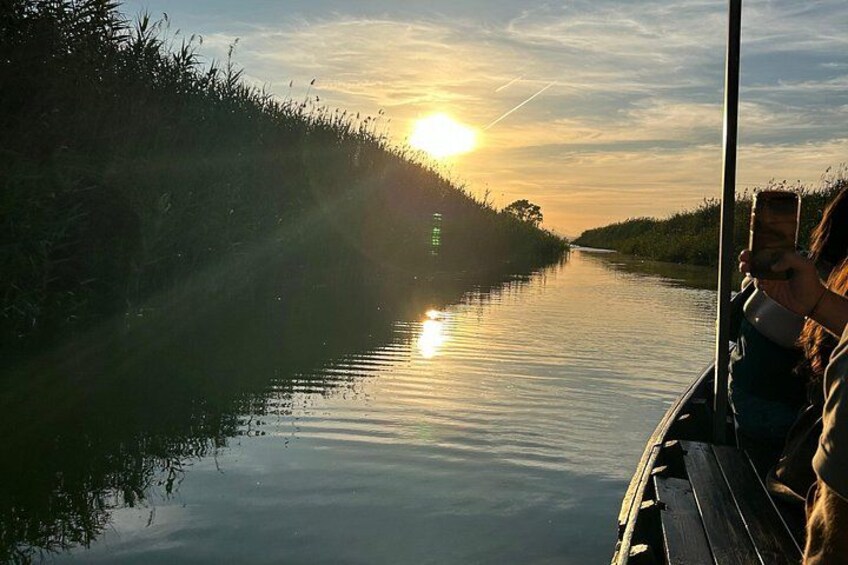 A river at sunset with a boat and a person holding a camera. 3