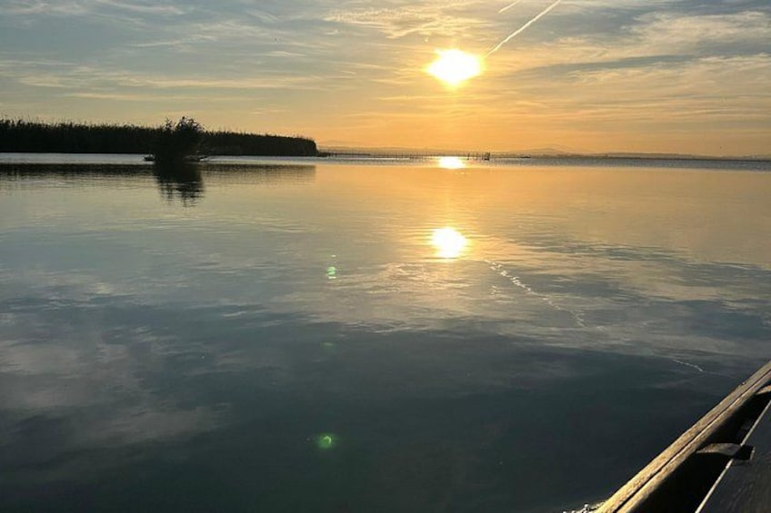 A calm lake at sunset with a boat dock on the right. 4