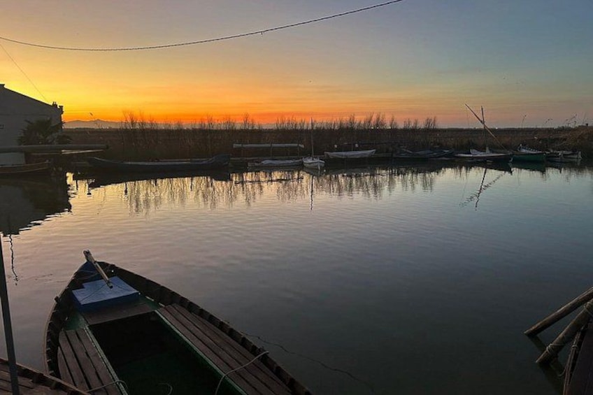 A calm river at sunset with boats docked along the shore. 1