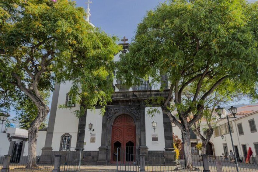 A church with a large wooden door, surrounded by trees and a fence. 3