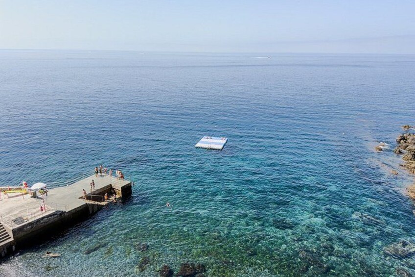 A pier extending into a clear blue sea with a small boat anchored in the water. 3