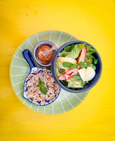 A meal with a salad, rice, and a dipping sauce on a plate. 3