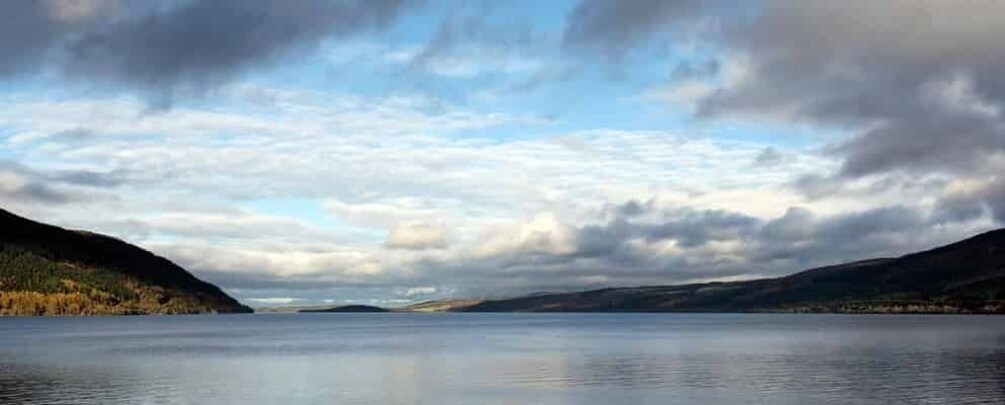A calm lake surrounded by hills with autumn foliage. 3