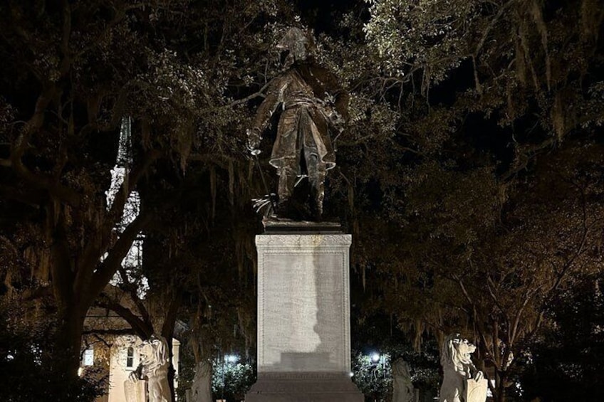A statue on a pedestal in a park at night. 4
