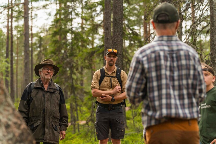 A group of people in a forested area with tall trees and dense greenery. 4