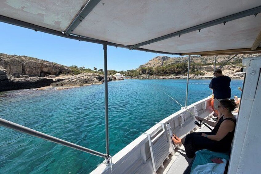 A boat on a calm sea with rocky coastline and clear skies. 4