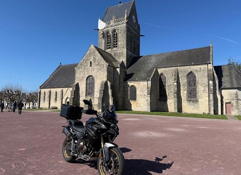 A historic church with a bell tower and a parked motorcycle in front. 1