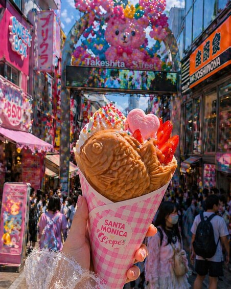 A hand holding a Santa Monica Crepes cone with a fish-shaped waffle and strawberries. 2
