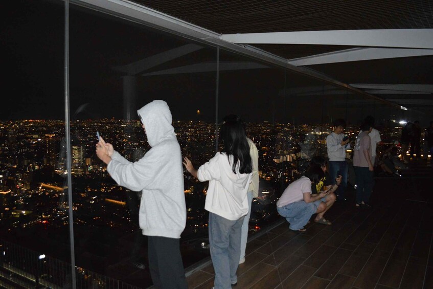 People standing on a high balcony overlooking a cityscape at night. 3