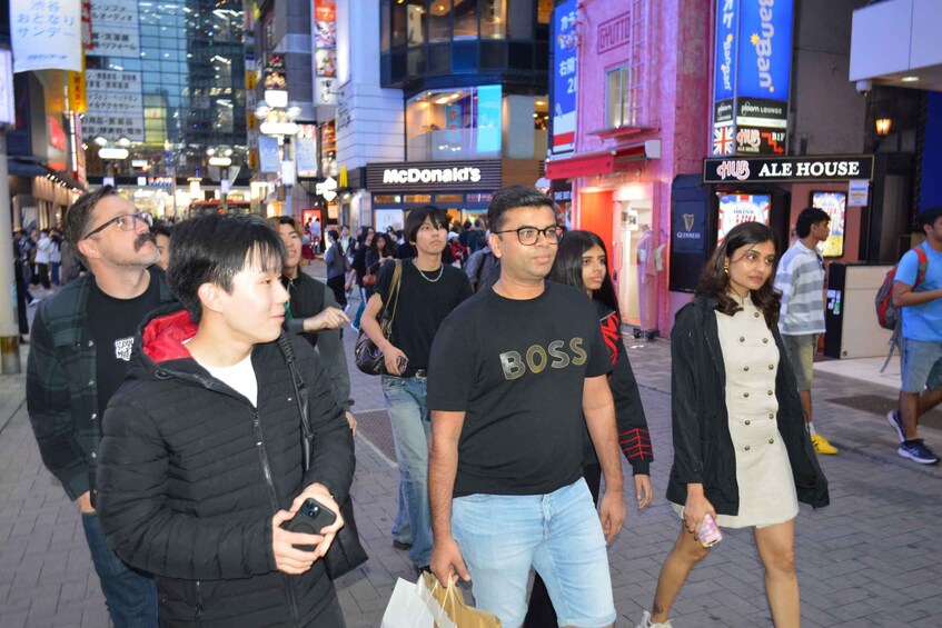A busy urban street with pedestrians, storefronts, and illuminated signs. 5