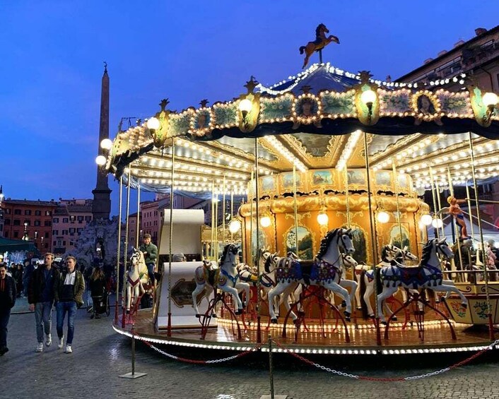 A carousel with horses and lights in an urban square at dusk. 1