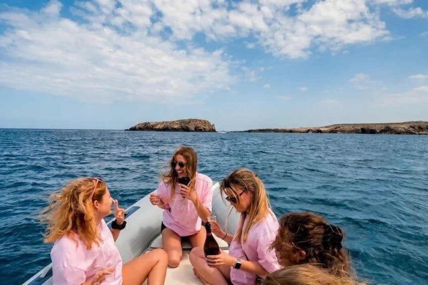A group of people on a boat in the sea with rocky land in the background. 2