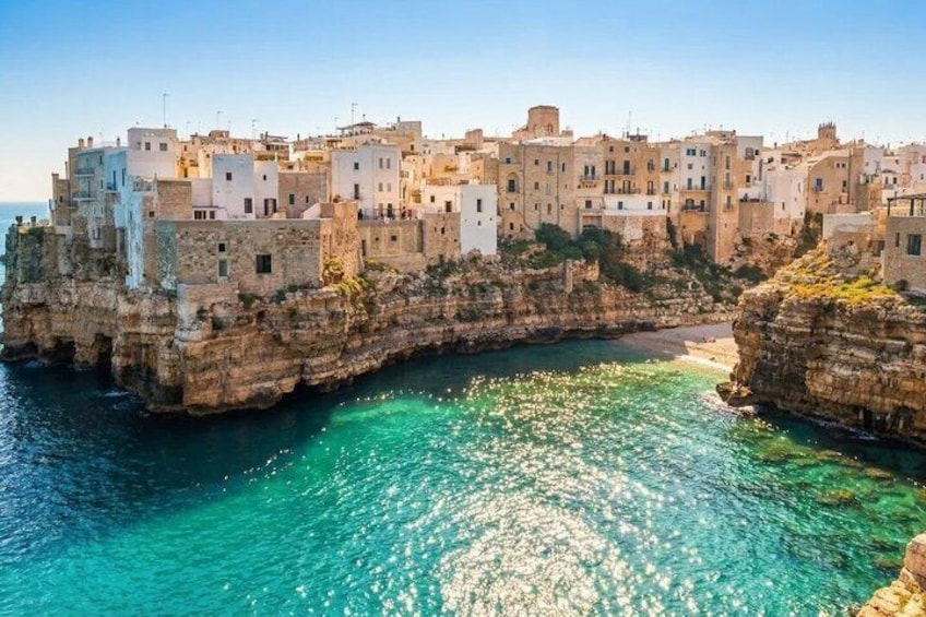 A coastal town built on a rocky cliff with clear turquoise waters. 3