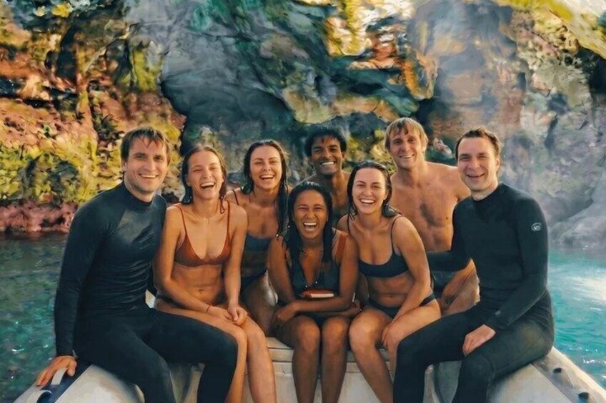 A group of people on a boat in a natural setting with rocky cliffs and clear water. 1