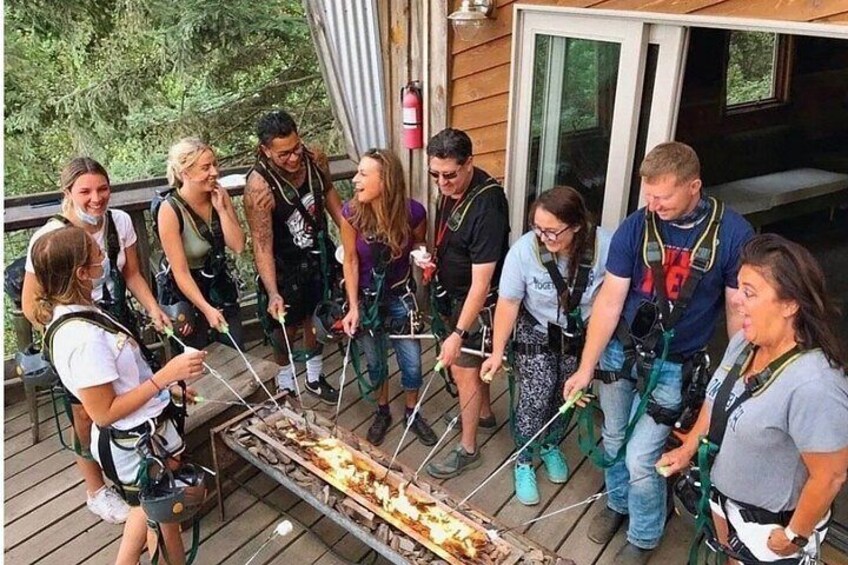 A group of people on a wooden deck preparing to cook food over an open fire. 5