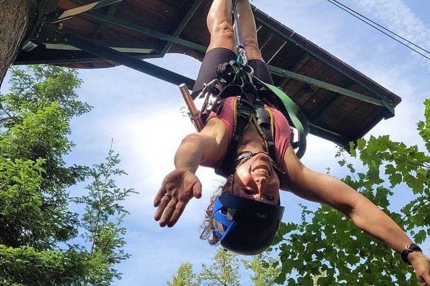 A person bungee jumping with a harness and helmet, with trees and a clear sky in the background. 3