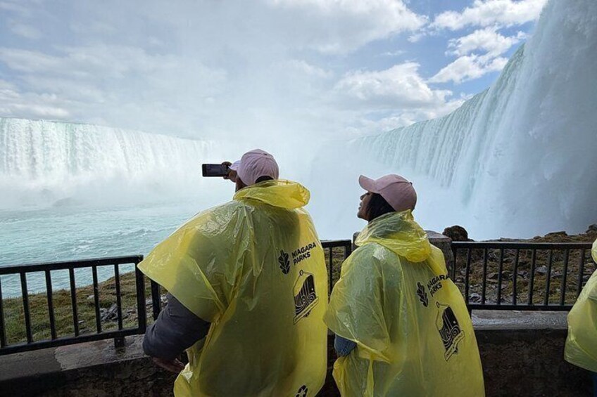 Two people in yellow rain ponchos taking a photo of a waterfall. 4